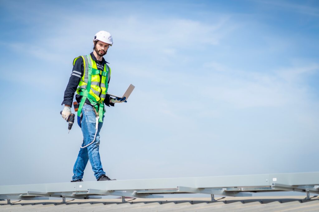 Male engineer installing or checking the working condition of solar panels on the roof