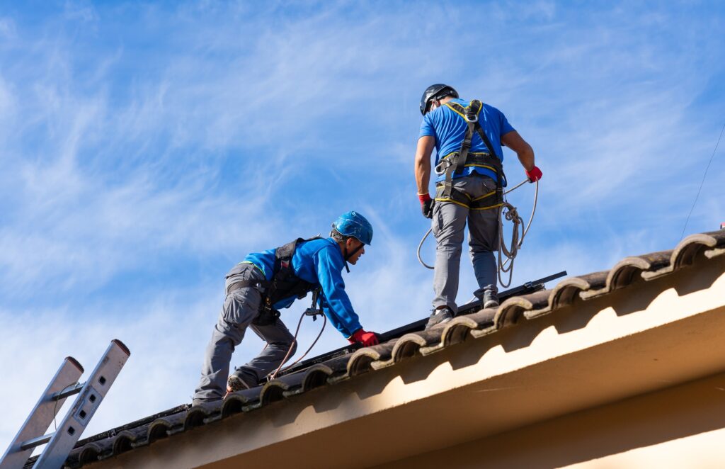 Workers installing solar panel on roof with safety harnesses
